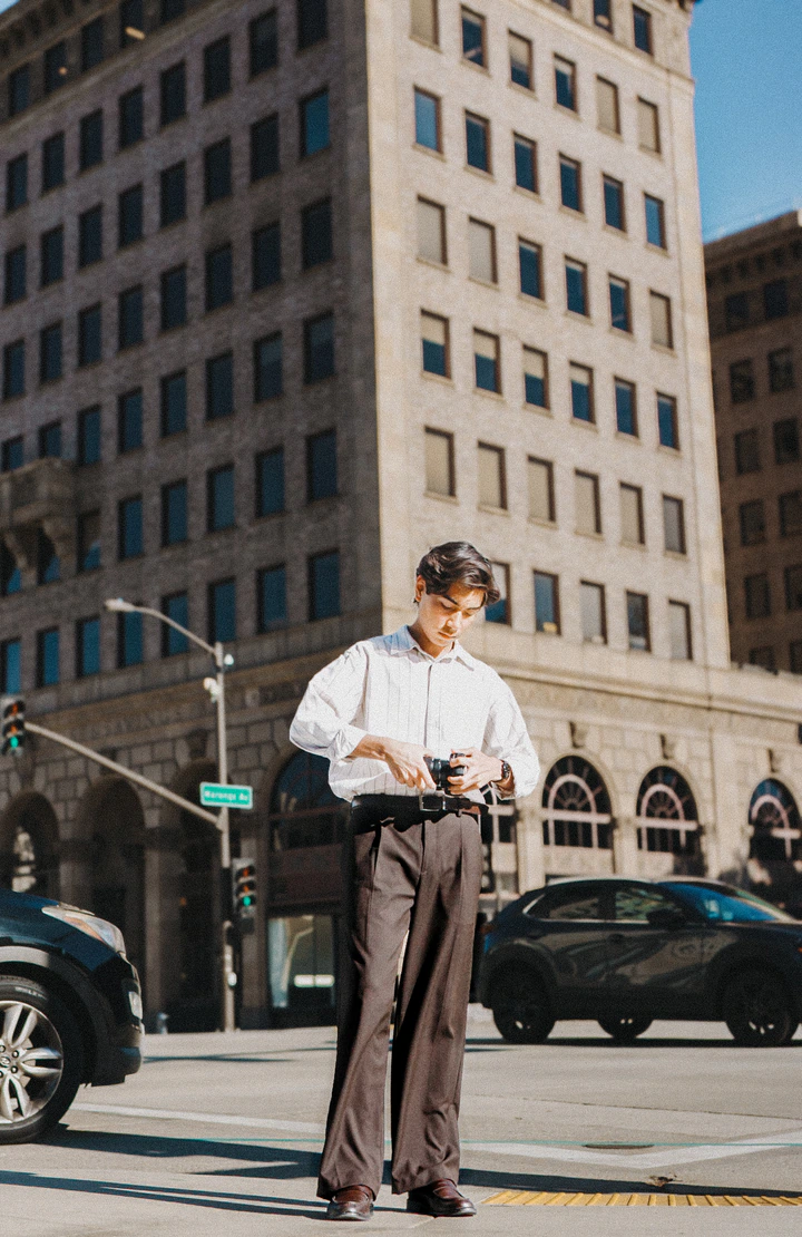 Kai checking his camera in front of a tall stone building