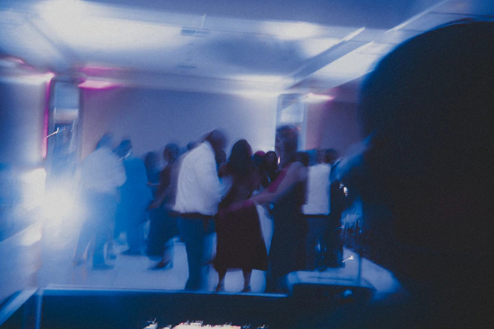 Crowded dance floor in blue light seen from the DJ booth