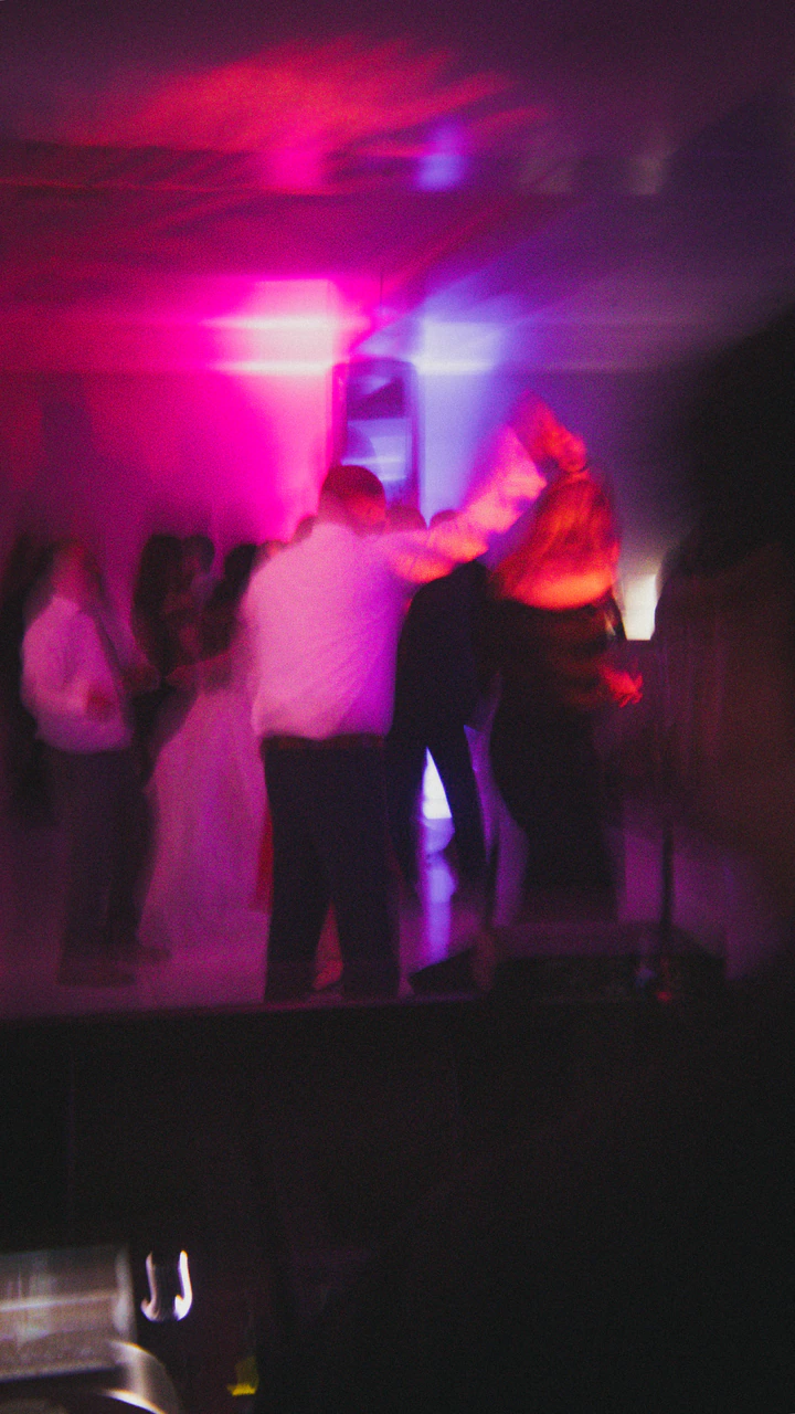 Guests dancing under pink and purple lights, blurred with motion