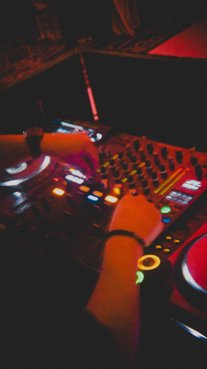 Hands on a DJ mixer under red light