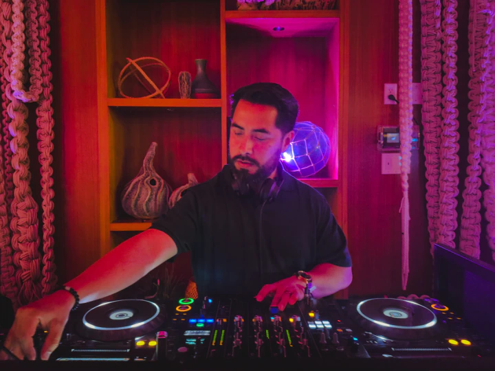 DJ with headphones around his neck working the decks at night