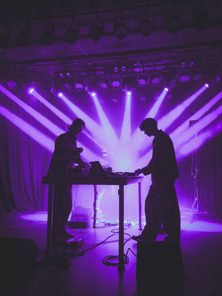 Two performers silhouetted against purple stage lights